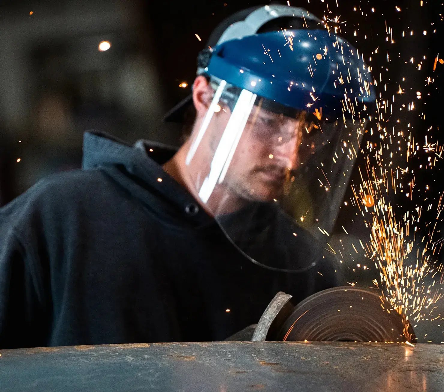 man-grinding-metal-with-face-shield-and-sparks