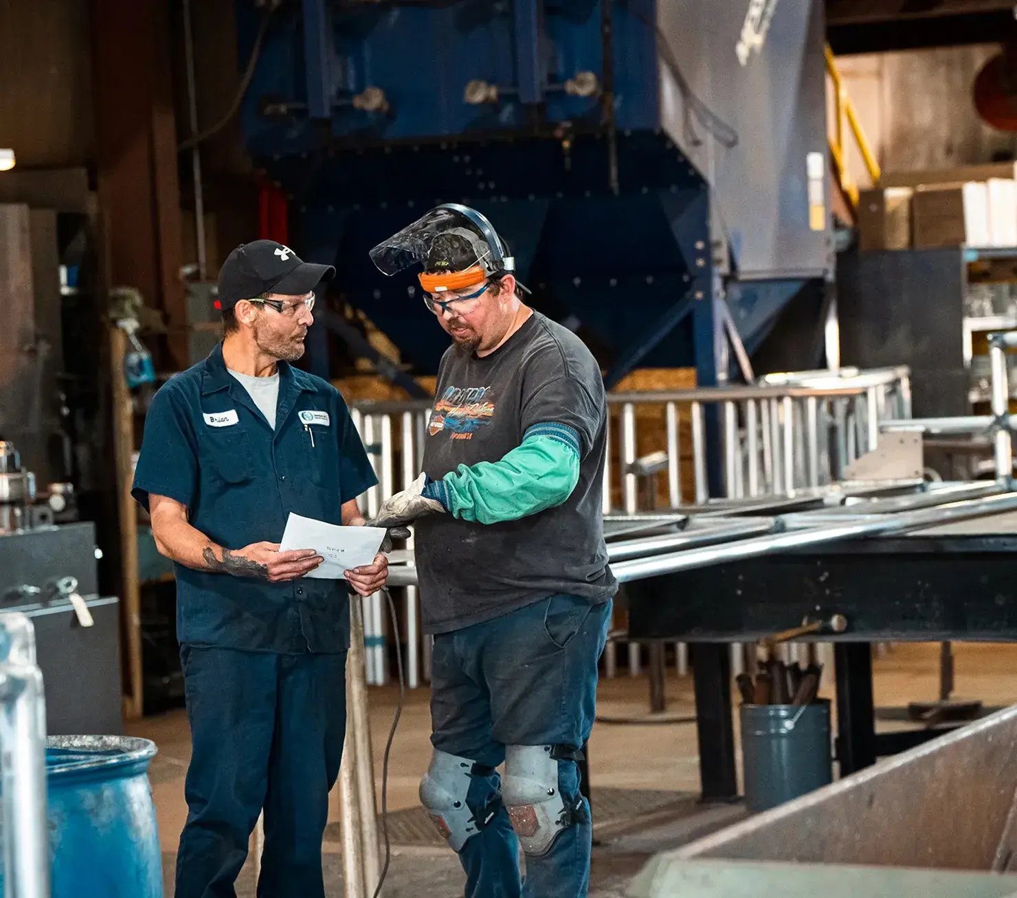 two-factory-workers-discussing-plans-in-workshop